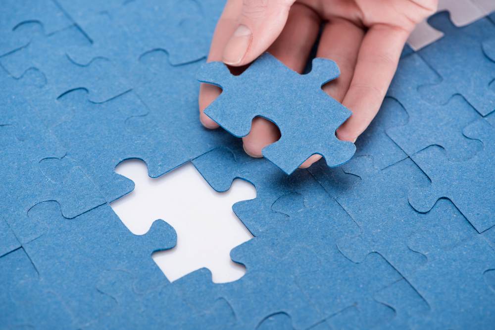 Cropped image of a businesswoman inserting the last missing puzzle piece, featuring 411 Business Law, highlighting the Differences Between Mergers and Acquisitions, and aligning with the page's context.