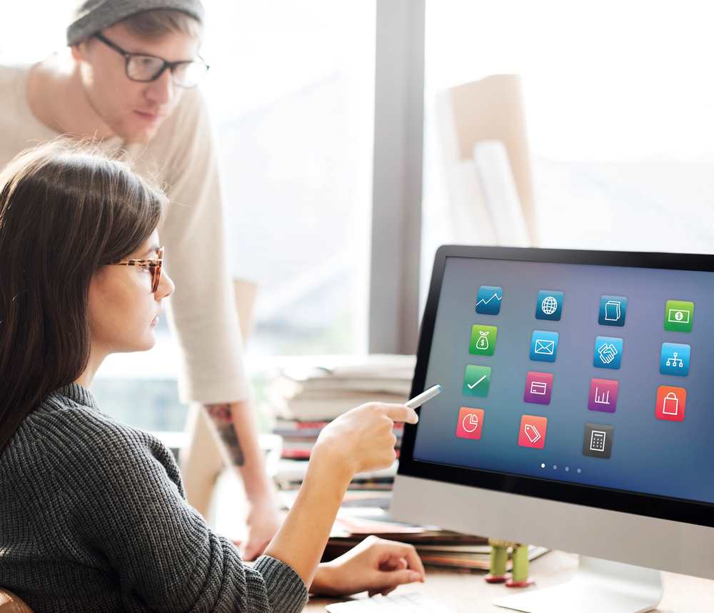 Image of a woman pointing at a monitor displaying various programs, featuring 411 Business Law and highlighting 'Implementing Compliance Programs,' ensuring it aligns with the page's context.