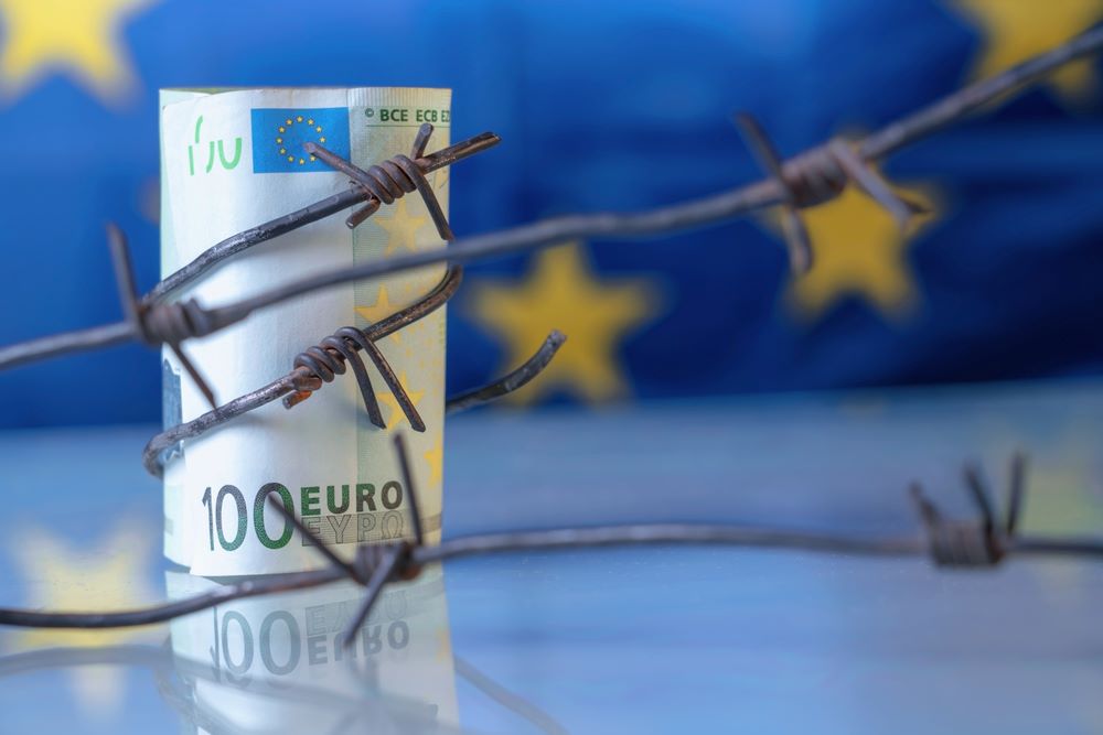 Image of close-up EU currency wrapped in barbed wire against the backdrop of the European flag, featuring 411 Business Law and highlighting 'International Sanctions and Embargoes,' ensuring it aligns with the page's context.