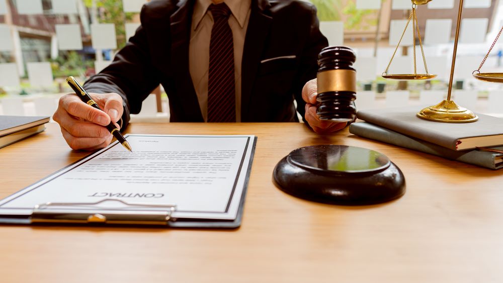 Image of a male lawyer working at a desk in an office, with the scales of justice prominently displayed, featuring 411 Business Law and highlighting 'Mitigating Legal Risks in Franchising,' ensuring it aligns with the page's context.