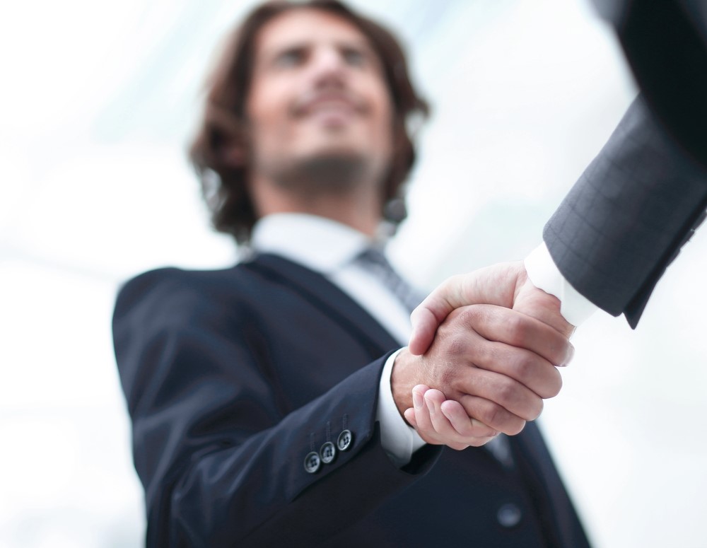 Image of two men in business suits shaking hands to signify agreement, featuring 411 Business Law and highlighting 'Successful International Business Ventures,' ensuring it aligns with the page's context.